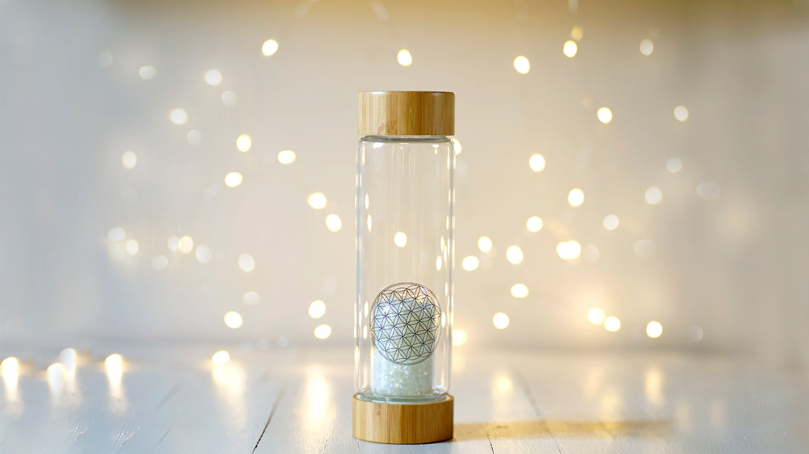 Cette gourde en verre au format nomade avec un bouchon et un socle en bambou vous permettra de vous hydrater à tout moment de la journée avec une eau dynamisée et informée par la fleur de vie et les cristaux.