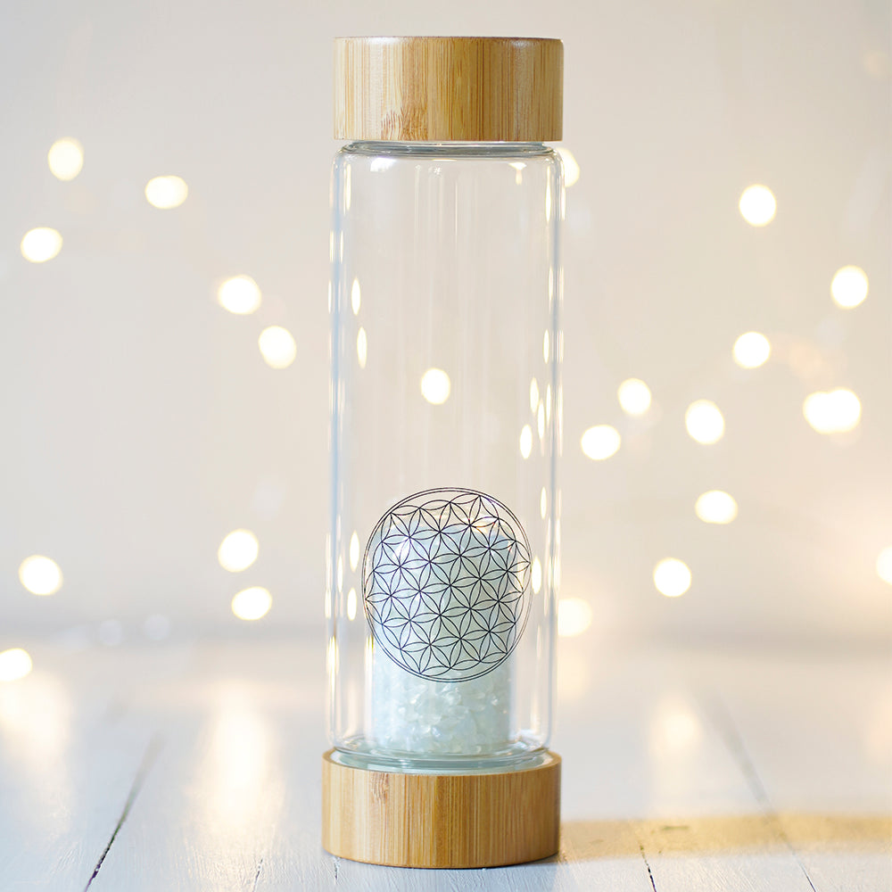 Cette bouteille Elixir minéral est en verre au format nomade avec un bouchon et un socle en bambou vous permettra de vous hydrater à tout moment de la journée avec :   - Une eau dynamisée (avec l'action bénéfique et puissante de la fleur de vie, motif de géométrie sacrée, sérigraphié sur le verre)   - Une eau informée (grâce à l'action combinée de l'énergie vibratoire des cristaux aux vertus énergétiques, logés dans un compartiment en verre vissé en bas de la bouteille et de la fleur de vie